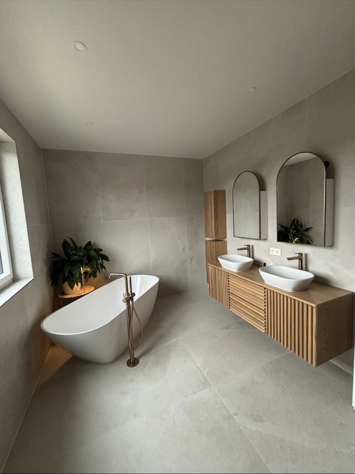 Helles Badezimmer mit freistehender Badewanne und großformatigen Fliesen